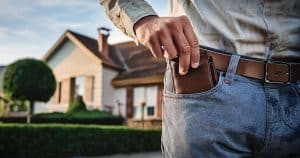 Man in front of house reaching into pocket for wallet